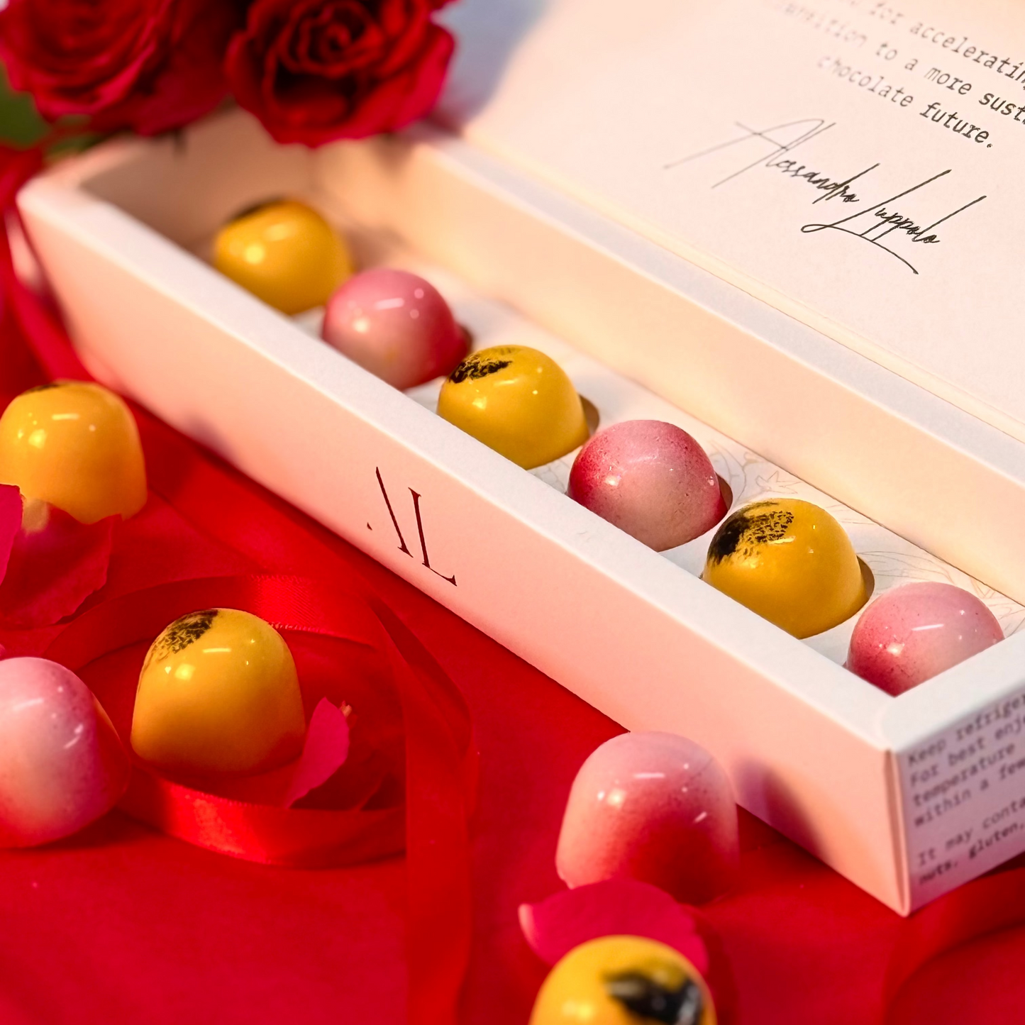 Chocolate truffles in a box with red roses on a red surface